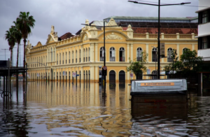 The historic Public Market of Porto Alegre partially submerged in floodwaters, with water reaching the base of the building's arched entrances.