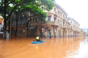 A person paddles a kayak through a flooded street outside the historic Correio do Povo building in downtown Porto Alegre, Brazil.